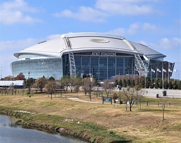 A modern stadium with a large, curved glass facade and the name "AT&T Stadium" displayed prominently. - Walk to FIFA World Cup! 1mi to AT&T Stadium - Texas Live! - GlobeLife Field. (Arlington)