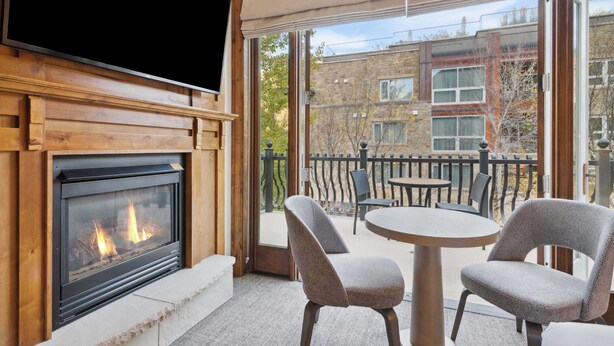 A cozy outdoor seating area with a fireplace, a television, and a view of the cityscape.