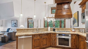 A modern kitchen with wooden cabinets, a built-in oven, and a large island with a sink.