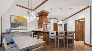 A modern kitchen with a central island, wooden cabinets, and pendant lighting.