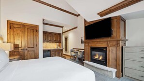 Une chambre spacieuse avec un grand lit, une cheminée et un téléviseur.