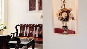 A room with a wooden bench, a table, and a wall-mounted vase with flowers. - Hong Tam Hotel (Ho Chi Minh City)