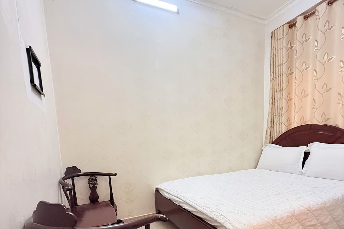 Een slaapkamer met een bed, een bureau met stoel en een raam met gordijnen.