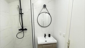 Un baño con ducha, lavabo, espejo e inodoro.