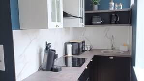Una cocina moderna con armarios blancos, salpicadero de mármol, encimera negra y suelo de madera.