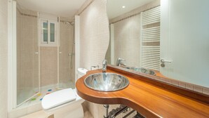 A bathroom with a wooden vanity, a sink, a toilet, and a shower area. - Sunset Villa Romani (Ca´n Picafort)