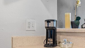 A kitchen with a coffee maker, a dishwasher, and a sink.