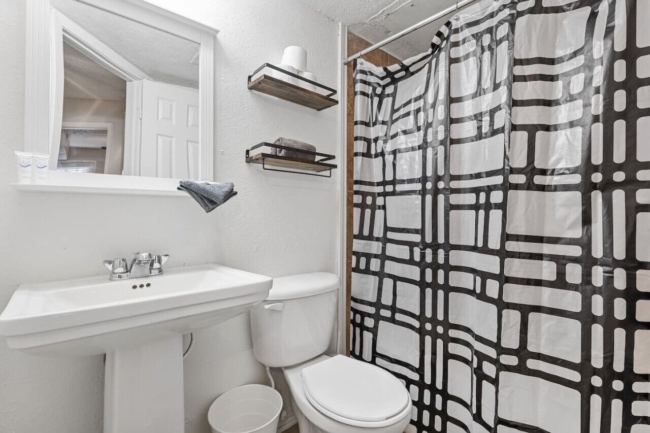 A bathroom with a white sink, a toilet, and a shower curtain with a geometric pattern.