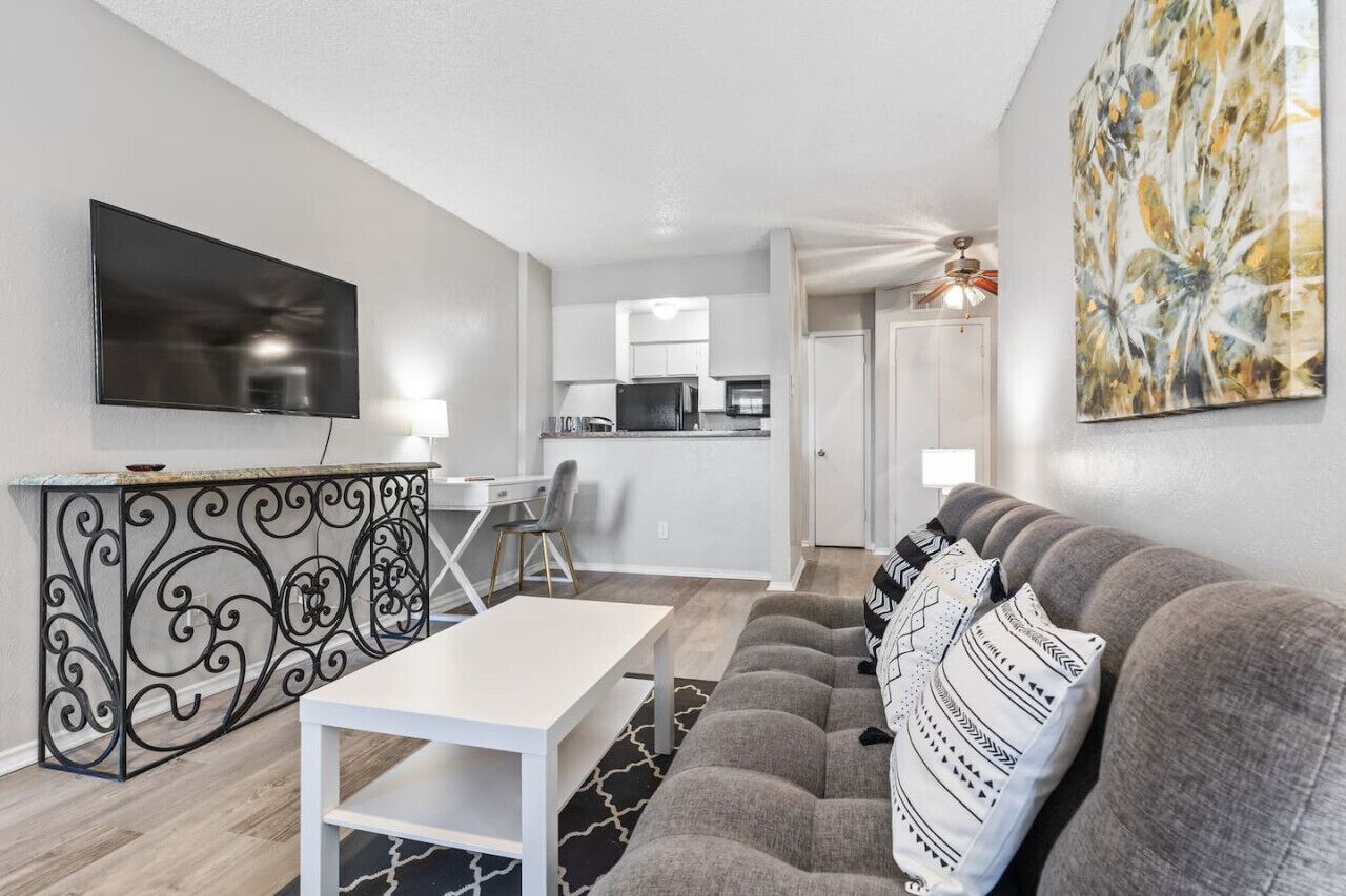 A modern living room with a sofa, a TV, and a dining area with a table and chairs.