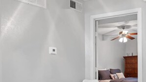 A room with a white table and two white chairs, a ceiling fan, and a bed with a wooden headboard. - Affordable & Convenient! Free WiFi! (Dallas)