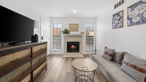 A living room with a fireplace, a television, a sofa, and a coffee table. - Cute & Contemporary 1 Bed Apt! Easy Pool Access! (Dallas)