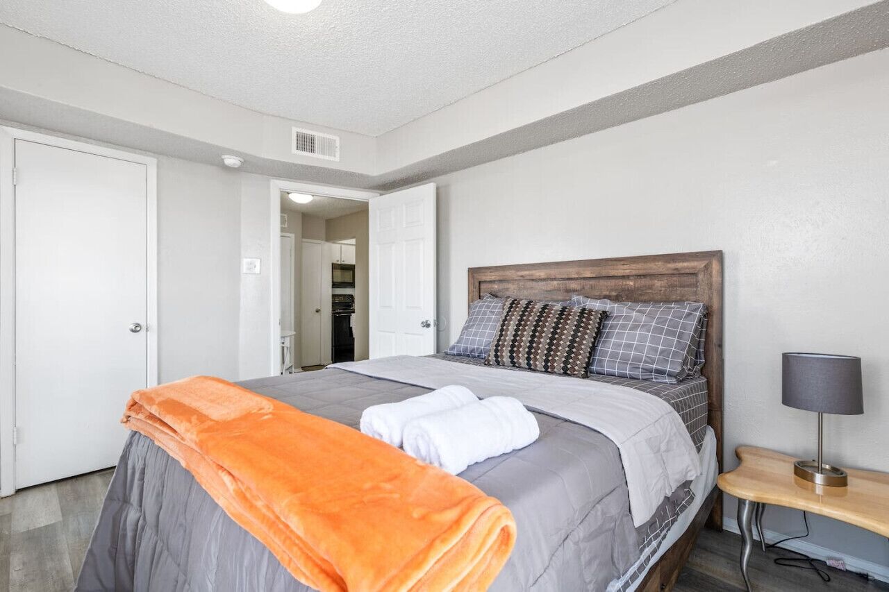 A bedroom with a bed, a nightstand, and a lamp.