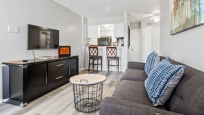 Un salon moderne avec un canapé gris, une table basse ronde et un meuble de rangement noir pour l’équipement audiovisuel.