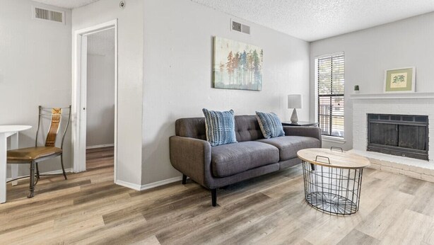 Un salon moderne avec un canapé gris, une table basse ronde et une cheminée.