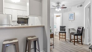 Una cucina moderna con mobili bianchi, un frigorifero in acciaio inossidabile e un angolo bar con sgabelli.