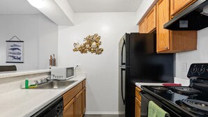 A compact kitchen with white countertops, wooden cabinets, a black refrigerator, and a black stove. - PERFECT FOR LONG STAYS! CENTRAL DFW (Dallas)