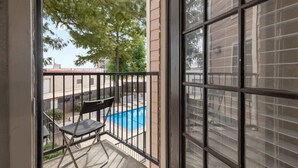 A balcony with a pool, a chair, and a table. - Simplicity and Convenience! Pool View w. Balcony! (Dallas)