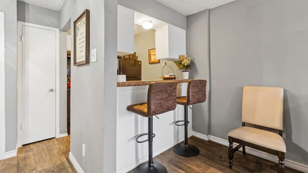 A modern kitchen with a bar area, two bar stools, and a chair. - COZY CORPORATE UNIT IN DFW! (Dallas)