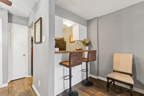 A modern kitchen with a bar area, two bar stools, and a chair.