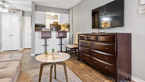 A modern living room with a flat-screen TV, a dark wooden dresser, and a round coffee table. - COZY CORPORATE UNIT IN DFW! (Dallas)