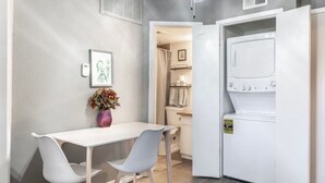 A compact kitchen with a white table and chairs, a washing machine, and a small dining area. - COZY CORPORATE UNIT IN DFW! (Dallas)