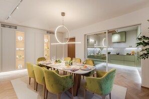 A modern dining area with a round table, green upholstered chairs, and a pendant light. - Casa Silvestro Modern Spacious 3 Bedrooms Luxury Apartment inside the Walls of Lucca (Lucca)