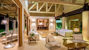 A spacious indoor area with a high ceiling, wooden beams, and a dining area with a modern chandelier.