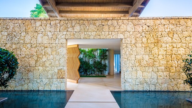A stone-walled building with a pool and a wooden decorative panel.
