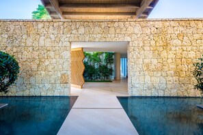 A stone-walled building with a pool and a wooden decorative panel.