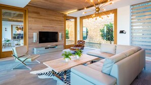 A modern living room with a large TV, leather sofa, and a unique ceiling light fixture.