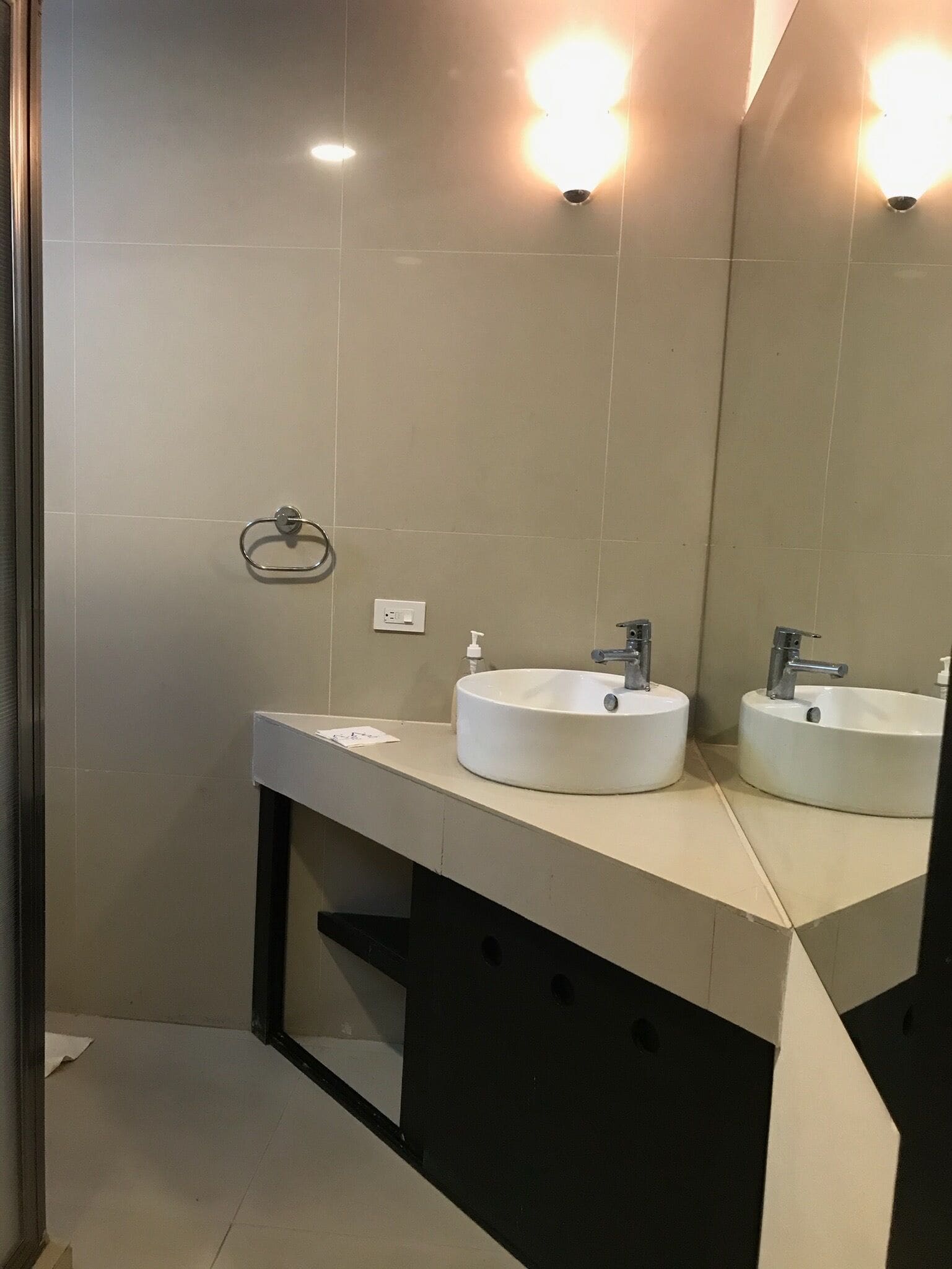 Un baño moderno con dos lavamanos redondos, un perchero y un espejo.