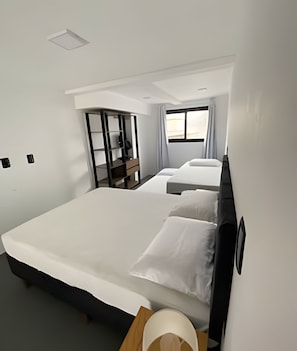 A hotel room with a large bed, a desk, a wardrobe, and a window. - Lofts Meia Morada (São Francisco do Sul)
