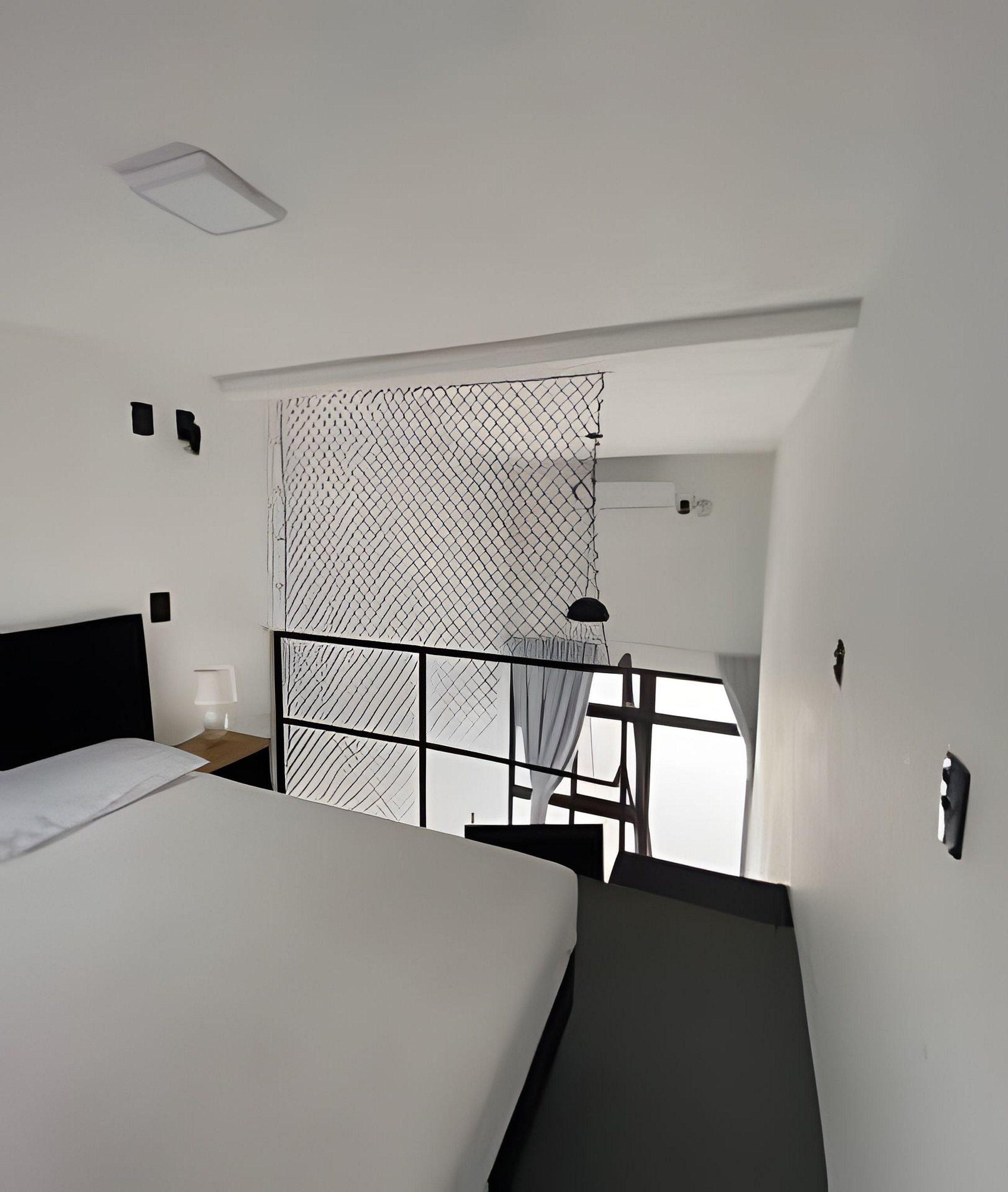 A hotel room with a bed, bedside table, lamp, and a window with a view.