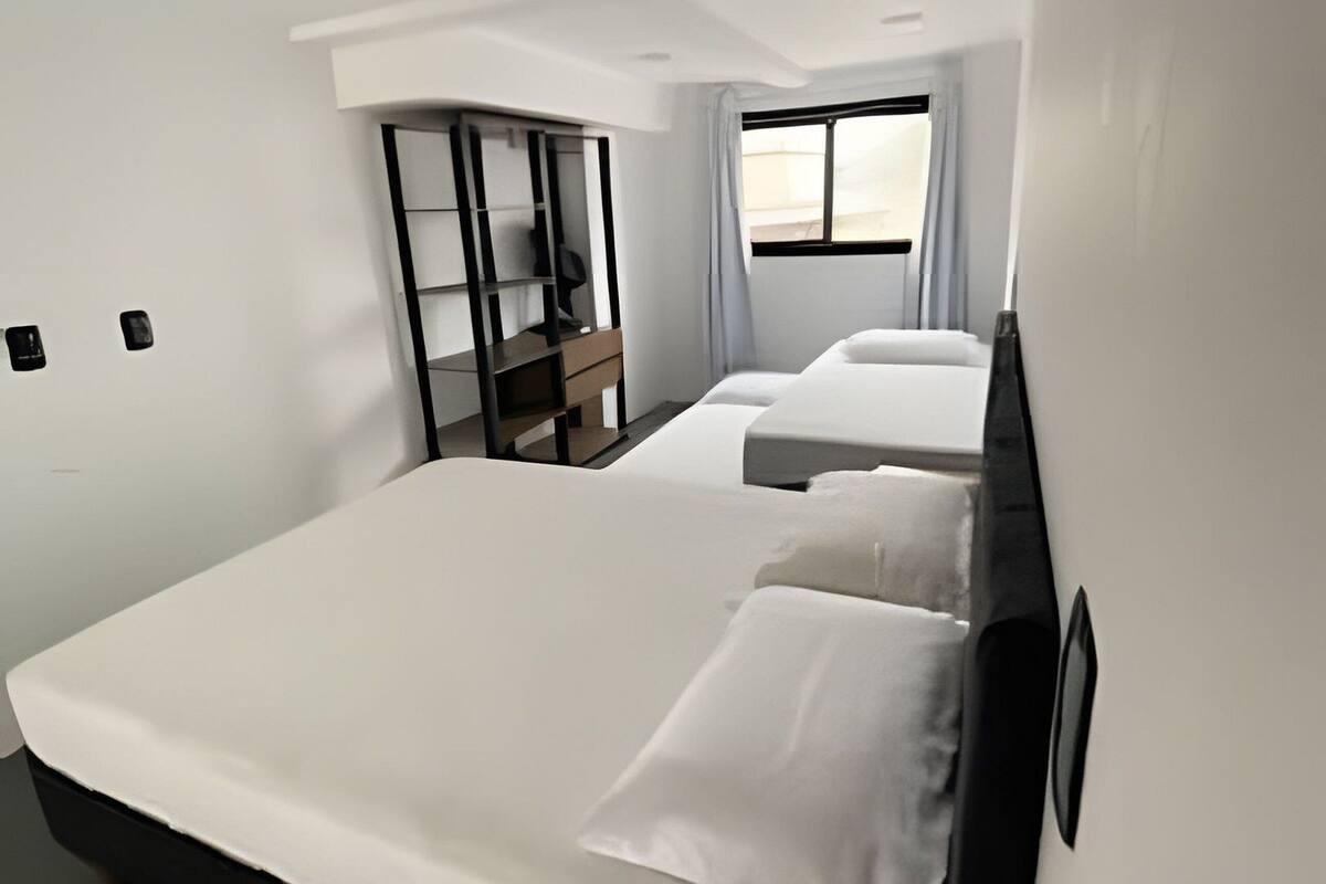 Moderni hotellihuone, jossa on suuri sänky, työpöytä ja ikkuna.