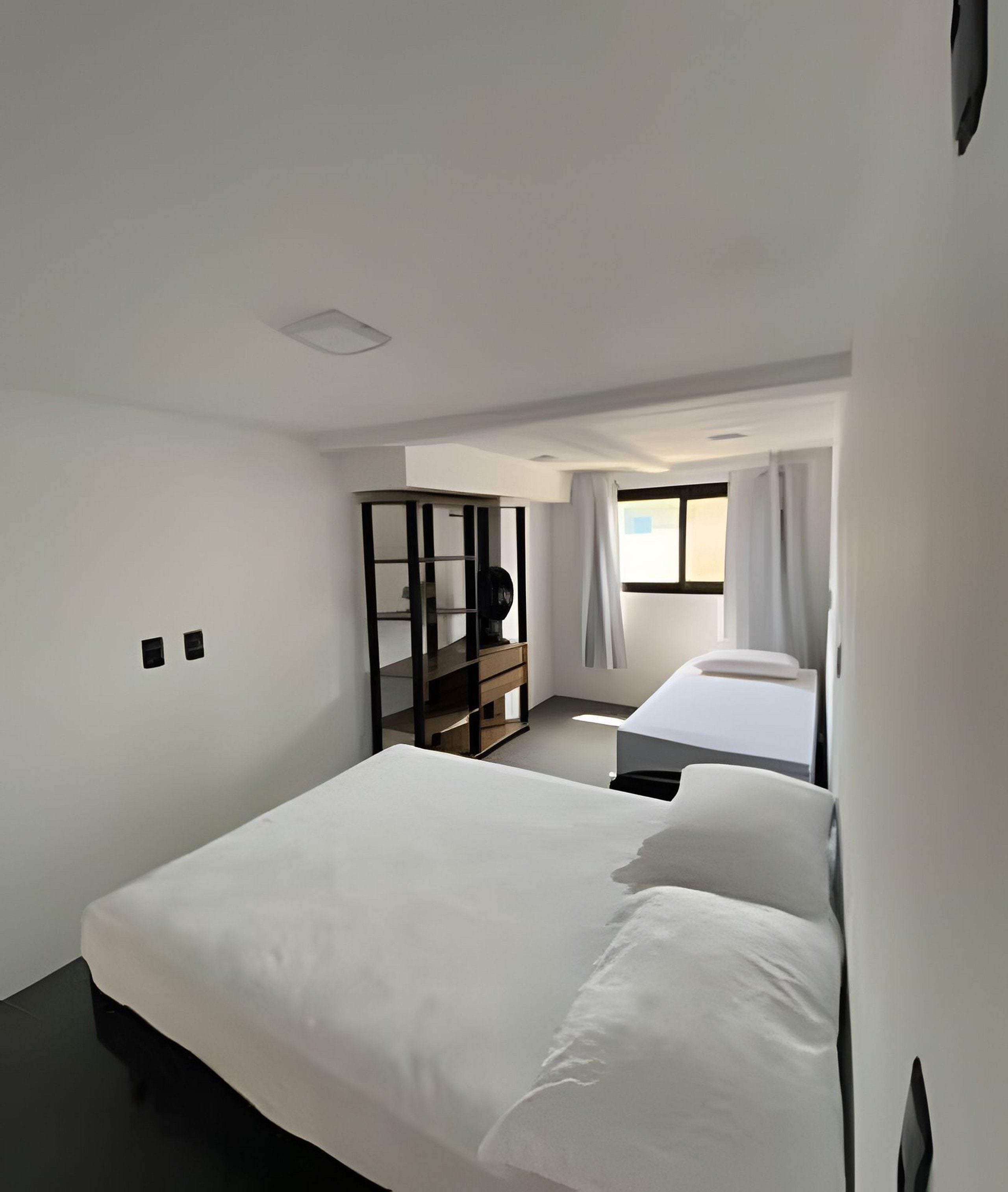 Ett hotellrum med en stor säng, ett skrivbord, en stol, en garderob och ett fönster med gardiner.