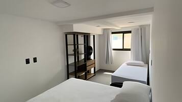 Ett hotellrum med en stor säng, ett skrivbord, en stol, en garderob och ett fönster med gardiner.