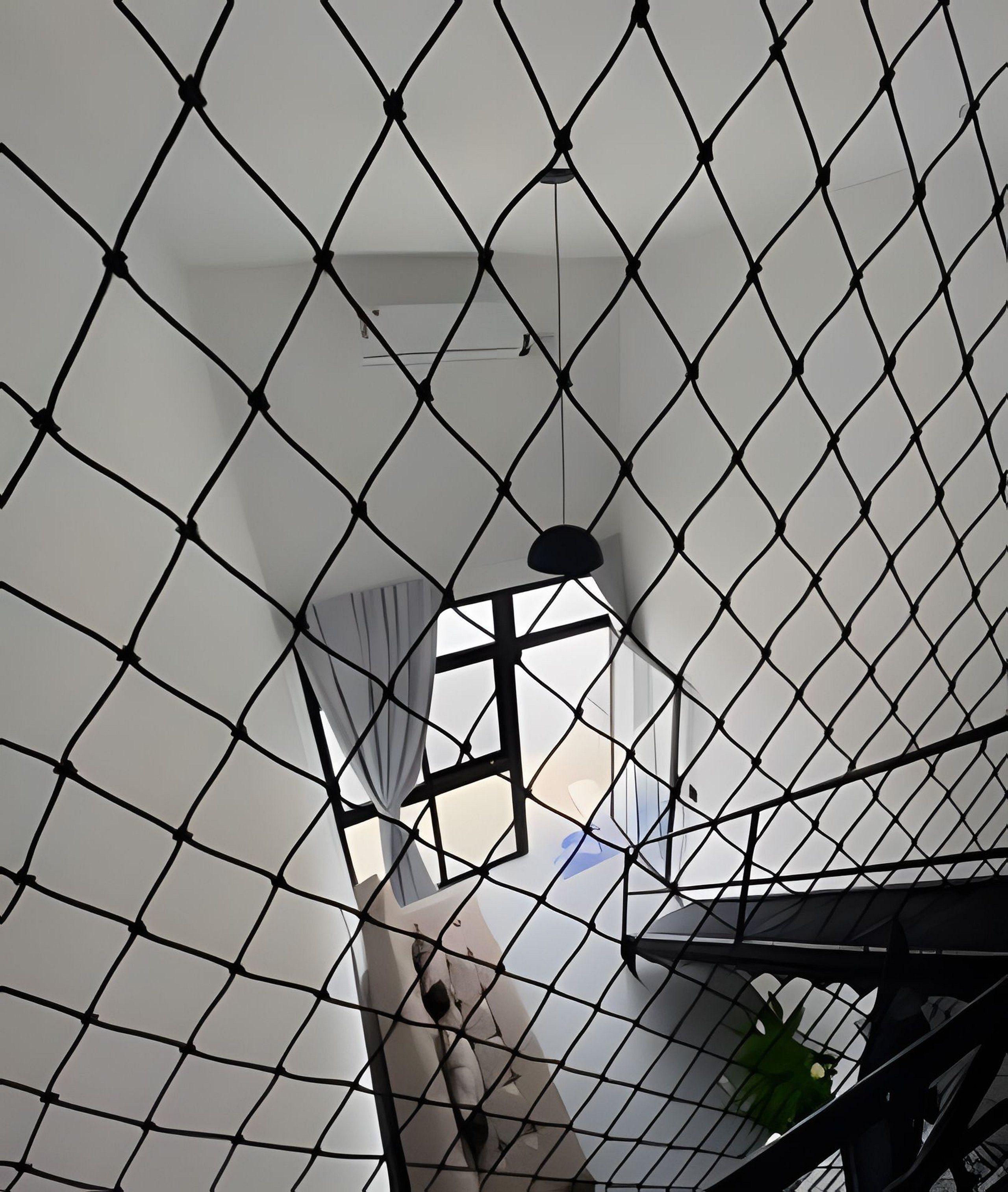 Ein Zimmer mit einem geometrisch gemusterten Decke, einem Fenster mit Vorhängen und einer Pendelleuchte.