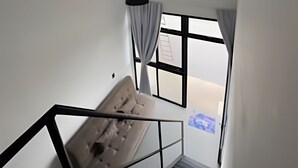 A modern interior with a staircase, a hanging light fixture, and a window with curtains. - Lofts Meia Morada (São Francisco do Sul)