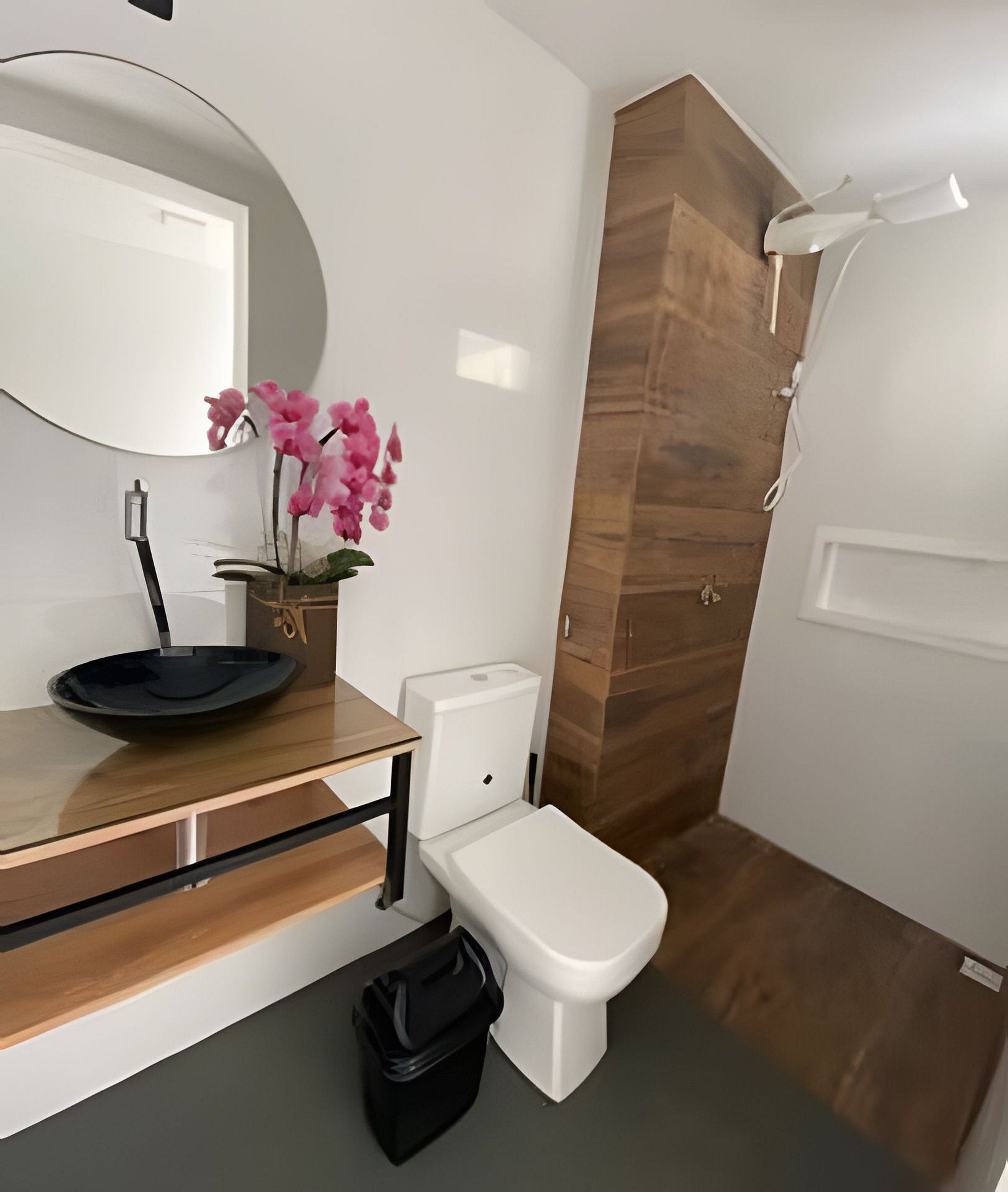Ein modernes Badezimmer mit einem Holzwaschtisch, einer Toilette, einem Waschbecken inklusive Spiegel und einer Duschkabine.