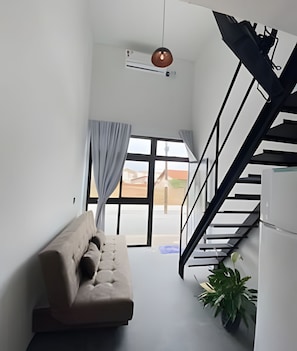 A modern interior with a staircase, a sofa, and a potted plant. - Lofts Meia Morada (São Francisco do Sul)