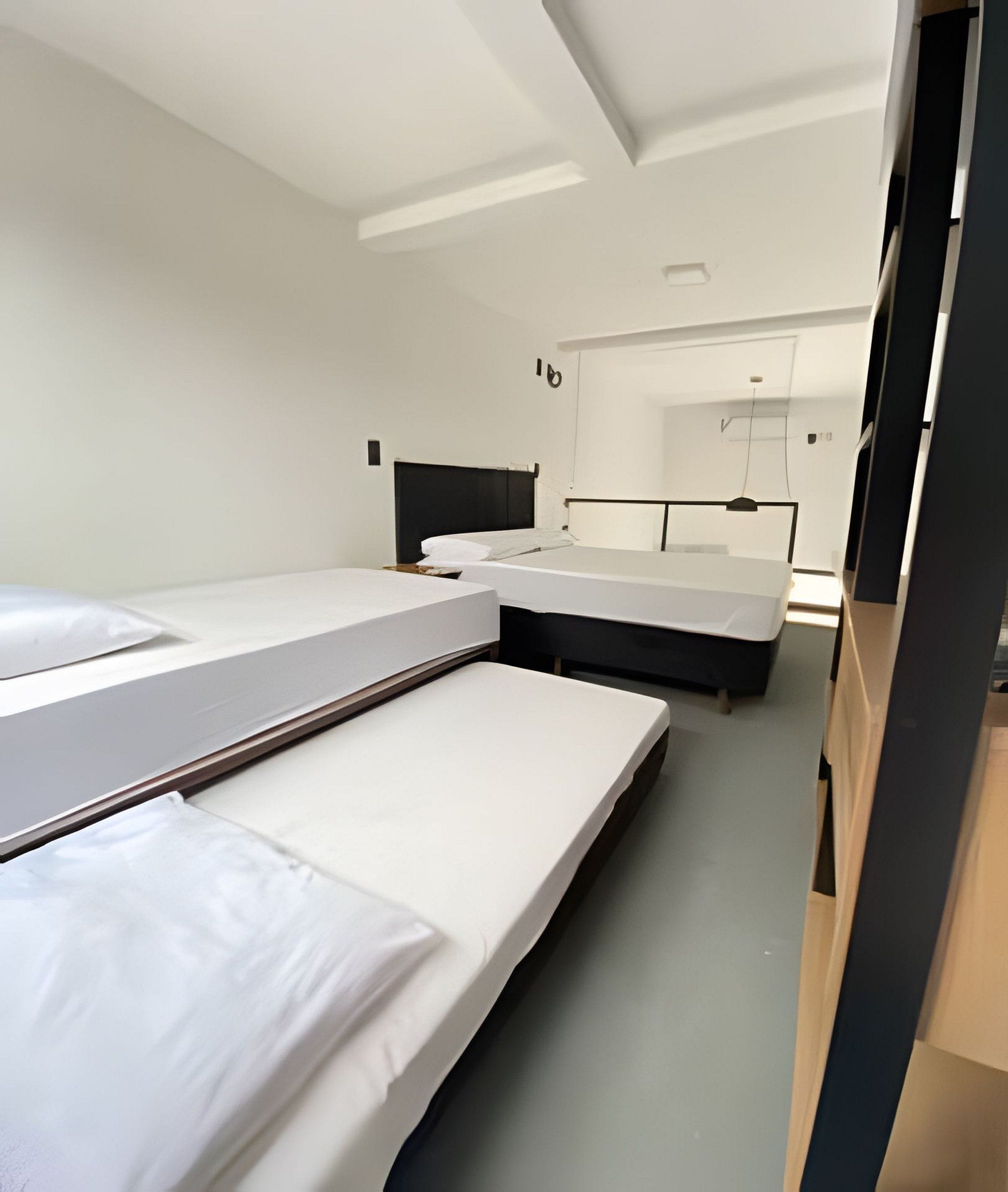 Une chambre d’hôtel avec deux lits, une armoire et un miroir.