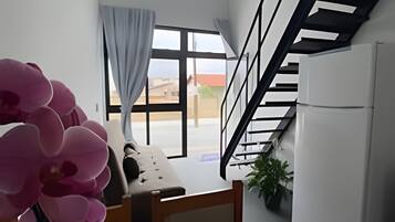 Une cuisine moderne dotée d’un réfrigérateur encastré, un coin repas avec une table et des chaises, un escalier et une grande fenêtre avec des rideaux.