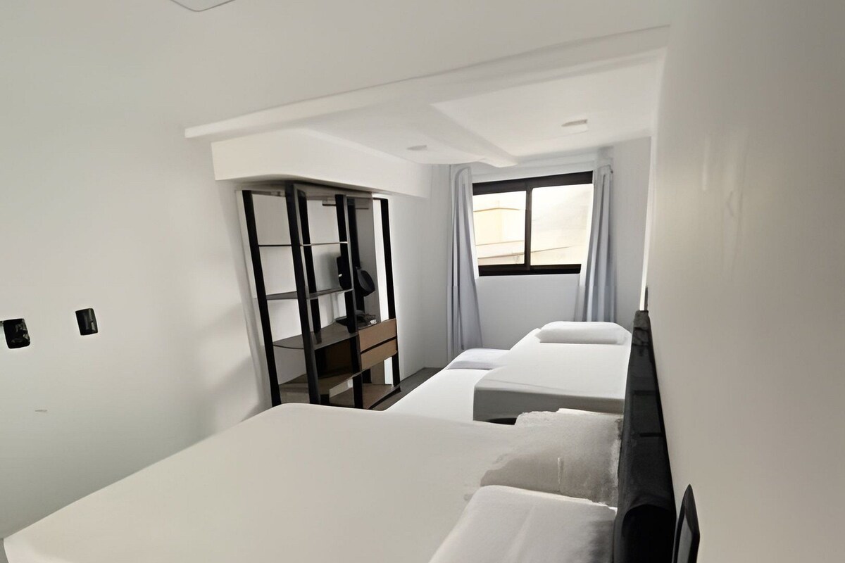 A hotel room with a large bed, a desk, a wardrobe, and a window.