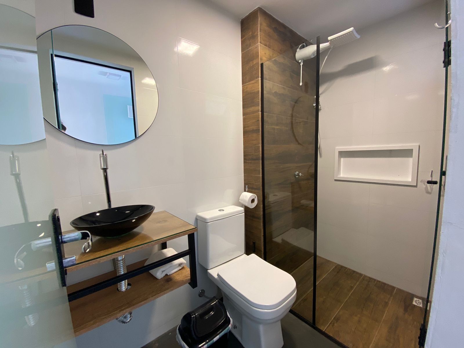 Ein modernes Badezimmer mit Duschkabine aus Glas, Toilette, Waschbecken und Spiegel.