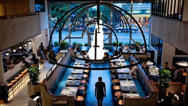 A modern restaurant with a central circular design, multiple dining tables, and a view of the street outside. - Chic, Spacious Pet Friendly Apt Near Attractions/Food/EWR/NYC (West Orange)