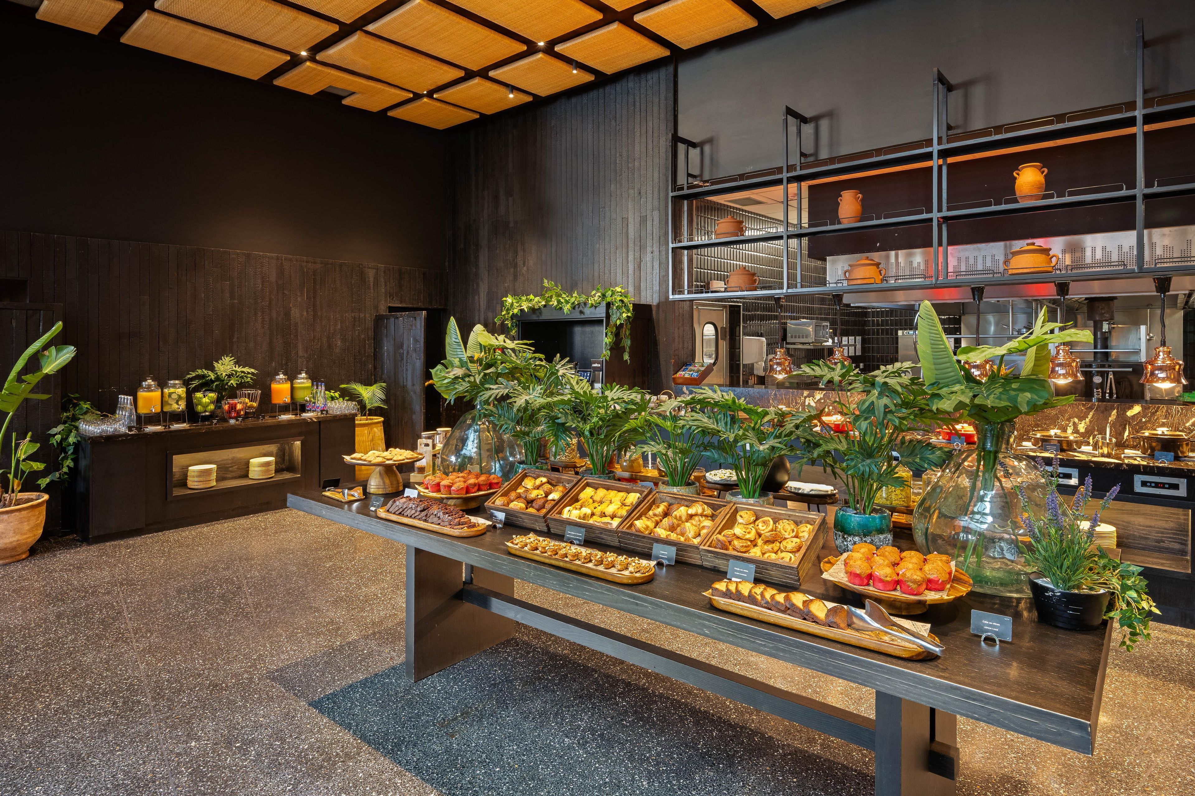 A buffet with various food items and a kitchen area in the background.