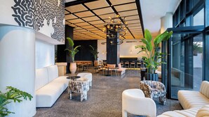 A modern lobby with a high ceiling, a unique black and white wall art, and a central seating area with a mix of sofas and armchairs. - Radisson Hotel Casablanca Gauthier La Citadelle (Casablanca)