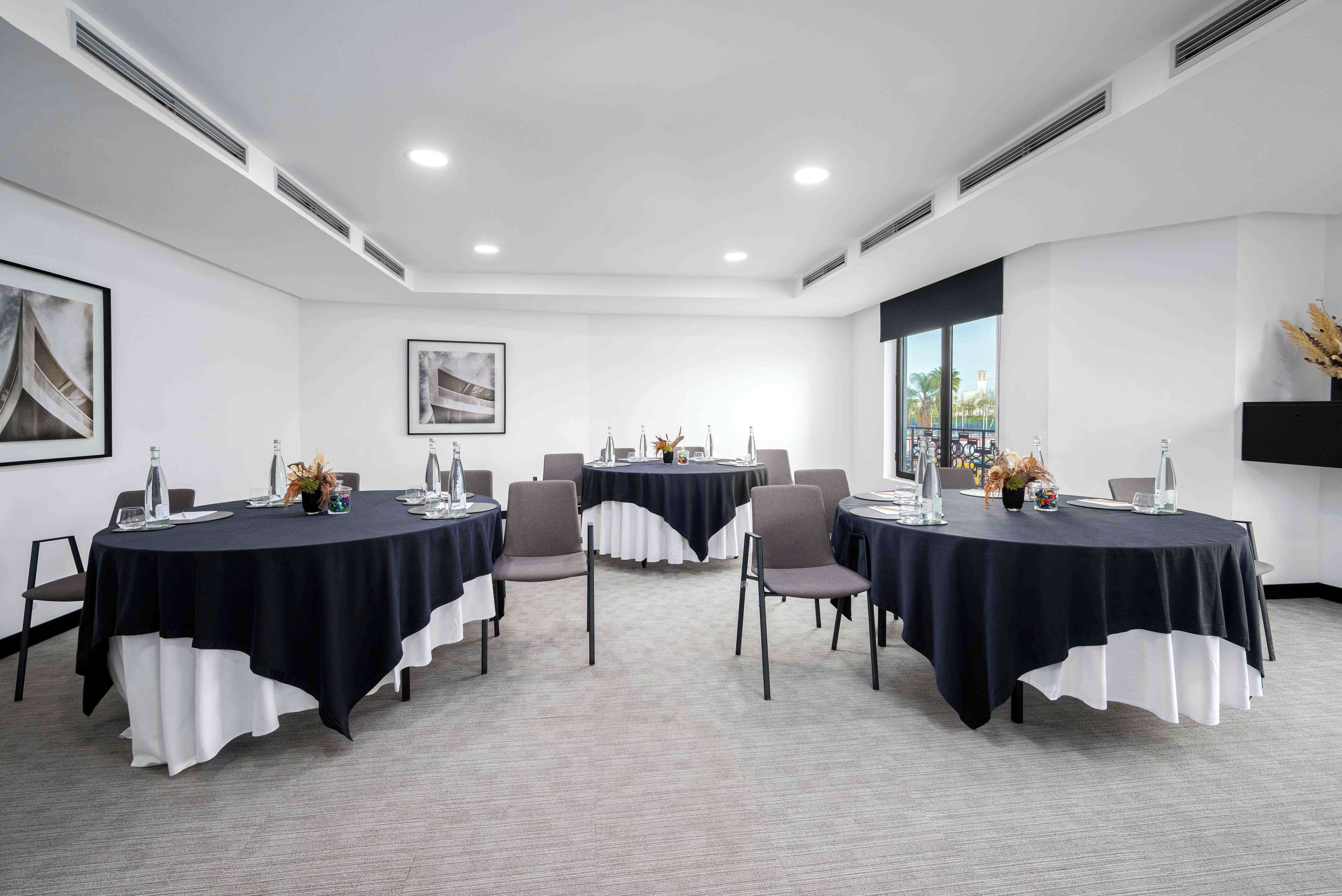 A conference room with round tables, chairs, and a large window.
