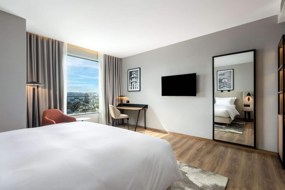 Une chambre d’hôtel moderne avec un grand lit, un bureau et une vue sur la ville.