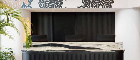 A modern reception area with a black and white marble reception desk, two black chairs, and a decorative wall with abstract patterns.